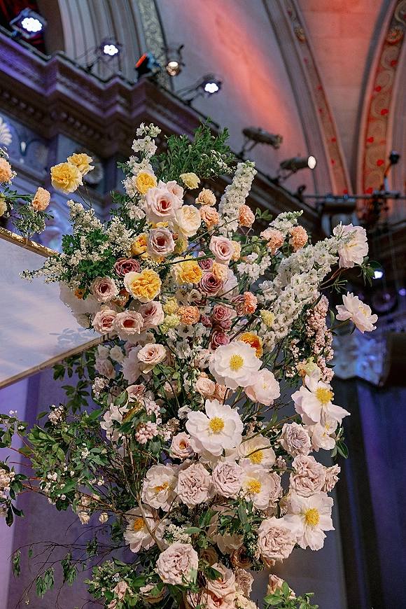 Wedding floral arrangement, ceremony floral installation with roses, cosmos, carnations and baby's breath draped on a balcony railing in an ornate venue