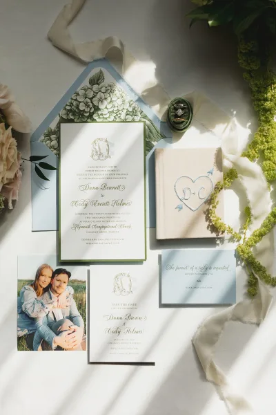 Invitation suite with botanical wedding invitations, wax seal, rings, silk ribbon and blush flowers on a white surface in natural light