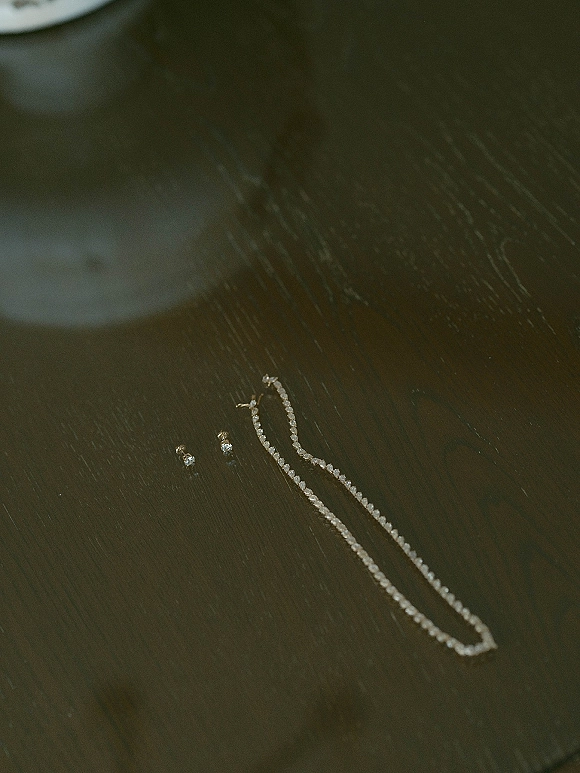Wedding jewelry bridal jewelry set with sparkling drop earrings and a gemstone tennis necklace arranged on a dark wooden surface