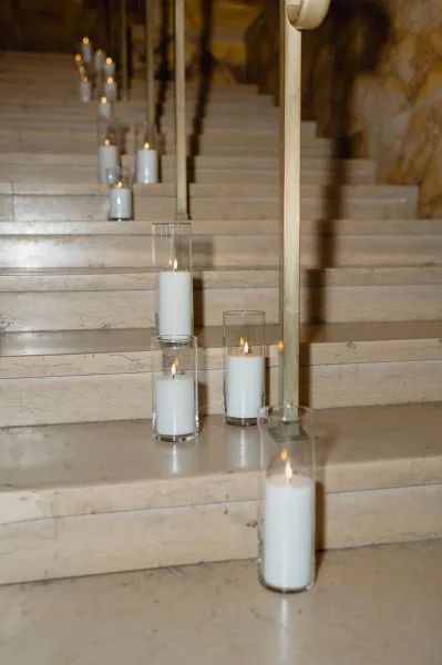 Candlelit staircase decor with wedding stairway candles in glass cylinder vases and white pillar candles lining a stone stair railing
