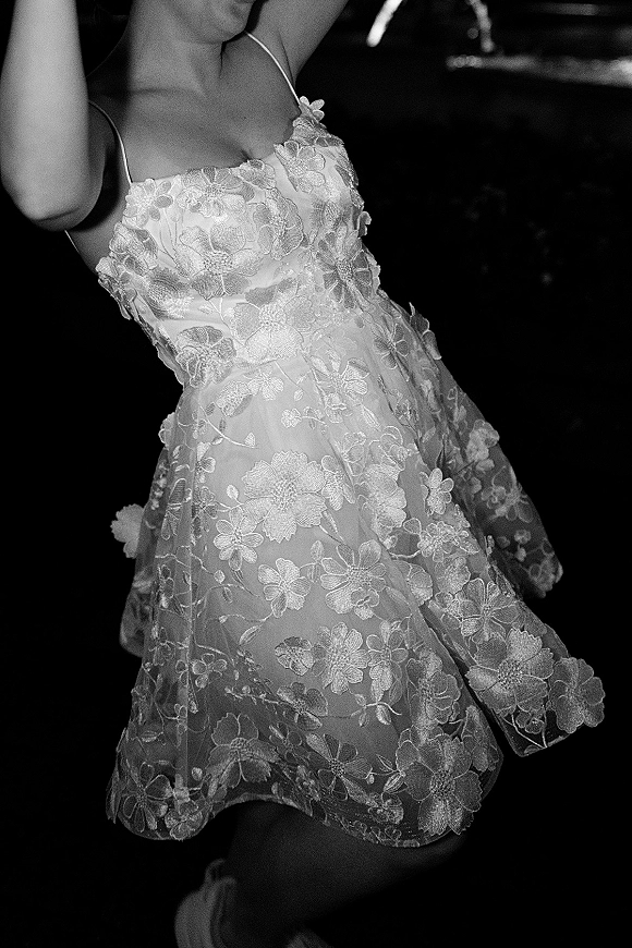 Wedding dress close-up showing floral lace wedding dress bodice with spaghetti straps and sweetheart neckline against a dark reception background