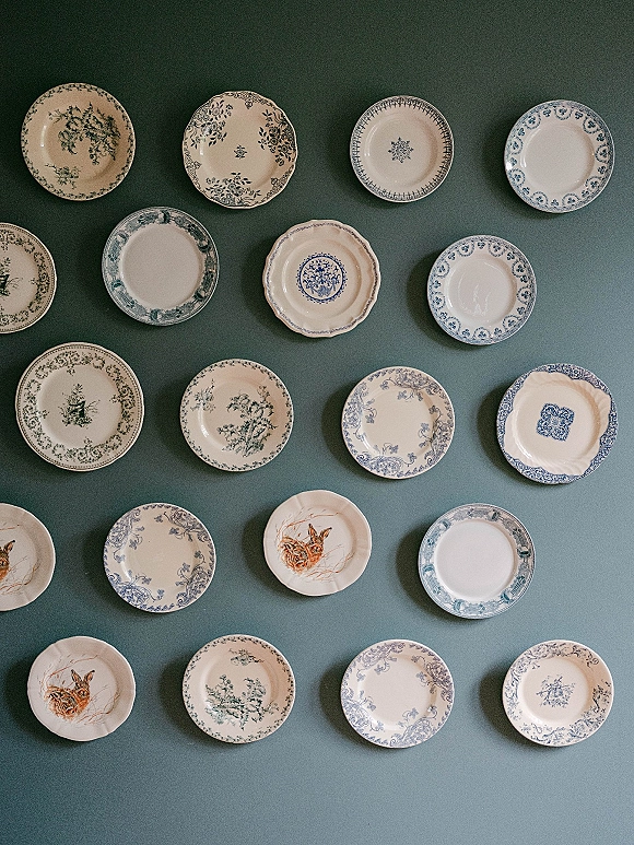 Wedding tableware with vintage wedding plates in blue and white patterns, arranged as a decorative wall display against a painted wall