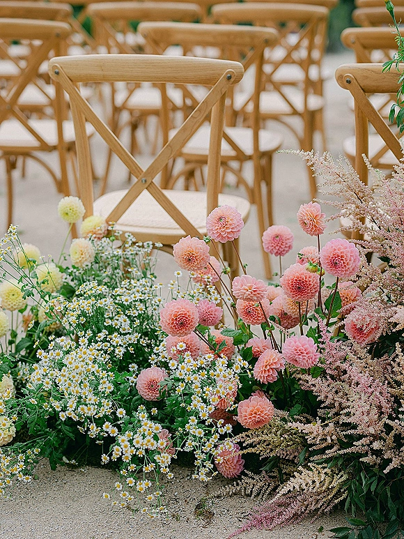 Ceremony aisle flowers with a wedding aisle flower meadow of pink dahlias, white daisies, and greenery lining a gravel outdoor path