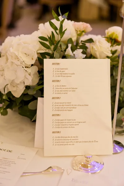 Wedding game card, a reception game idea, set in a card holder on a white tablecloth at an indoor reception table.