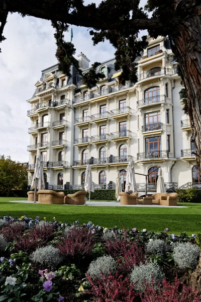 Hotel wedding venue featuring an outdoor wedding lounge on a manicured lawn, with wicker lounge furniture before historic hotel balconies.