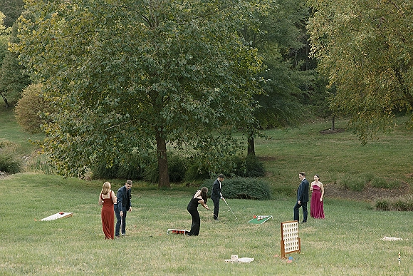 Wedding lawn games set up on a grassy park lawn with cocktail hour lawn games like cornhole, giant connect four, and croquet for guests in formalwear