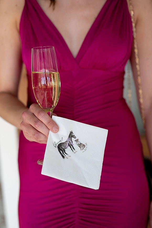Wedding cocktail napkin and custom cocktail napkins wedding held beside a champagne flute, sparkling wine, and magenta dress with gold chain strap