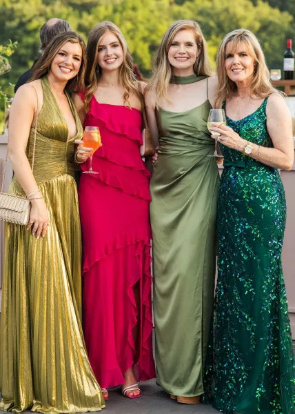 Wedding guests portrait captured as a cocktail hour group photo, with guests raising cocktail glasses on an outdoor patio amid garden trees.