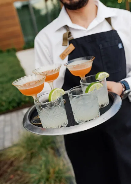 Wedding cocktails on a serving tray offer cocktail hour ideas, displayed neatly on a garden lawn with modern building backdrop.