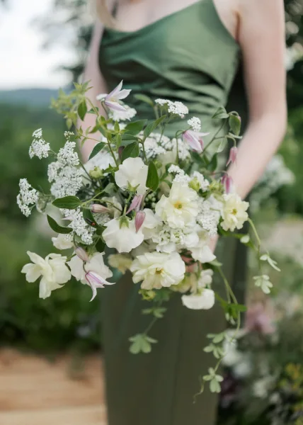 bouquet close-up of a bridesmaid bouquet with blooms and delicate vines, set amid garden foliage in an outdoor setting.