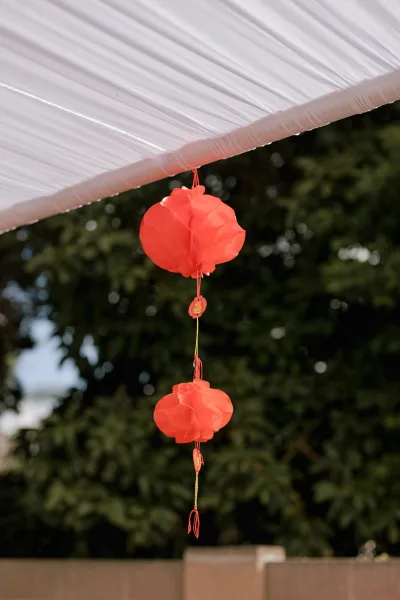 Hanging lantern decor with red paper lanterns strung beneath a white fabric canopy, floating above tree foliage and open sky