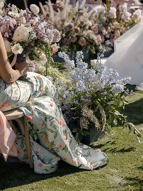 Wedding floral decor with pastel wedding flowers in garden roses, lavender, and blue delphinium lining a grassy aisle under a white tent