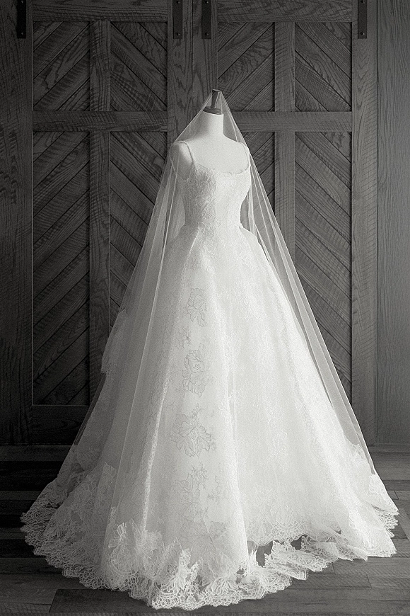 Wedding dress with lace wedding dress ball gown silhouette on a mannequin, long veil cascading over the train before rustic barn doors