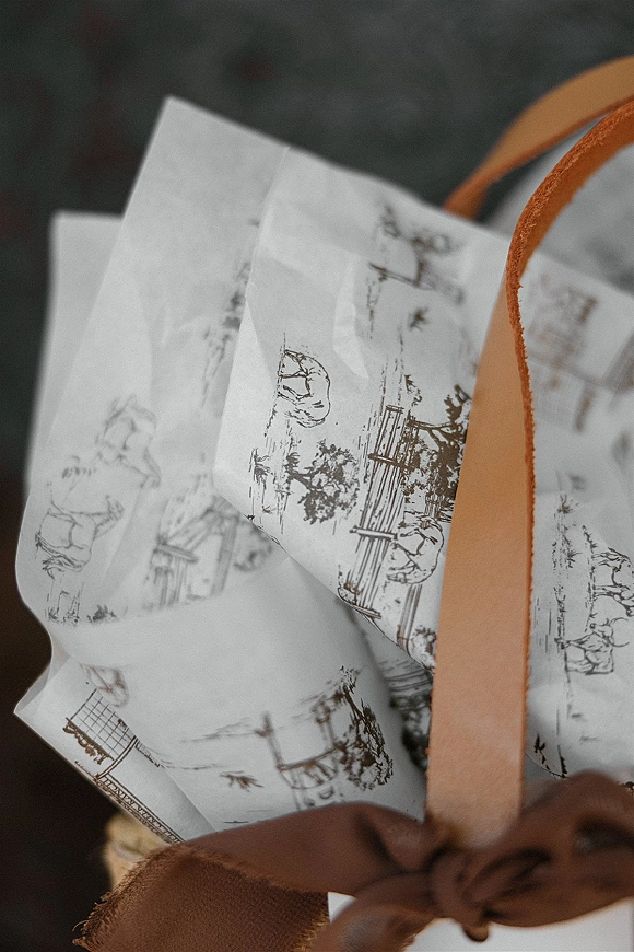 Wedding invitation suite with illustrated wedding invitations, patterned paper, envelope, ribbon wrap, and wax seal on a neutral surface