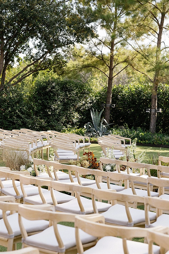 Ceremony seating with outdoor wedding ceremony chairs in neat rows, white cushions, and aisle florals on a garden lawn with agave plants