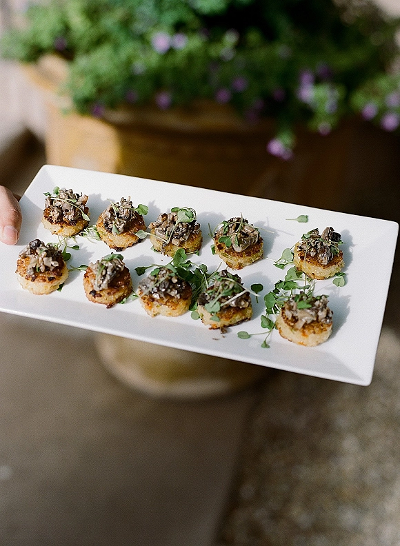 Wedding appetizers on a rectangular serving platter with bite-size canapes, microgreens garnish, and mushroom topping on an outdoor patio