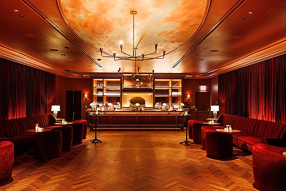 Cocktail lounge setup for wedding cocktail hour lounge with velvet banquette seating, candlelit tables, and chandelier under a painted ceiling mural