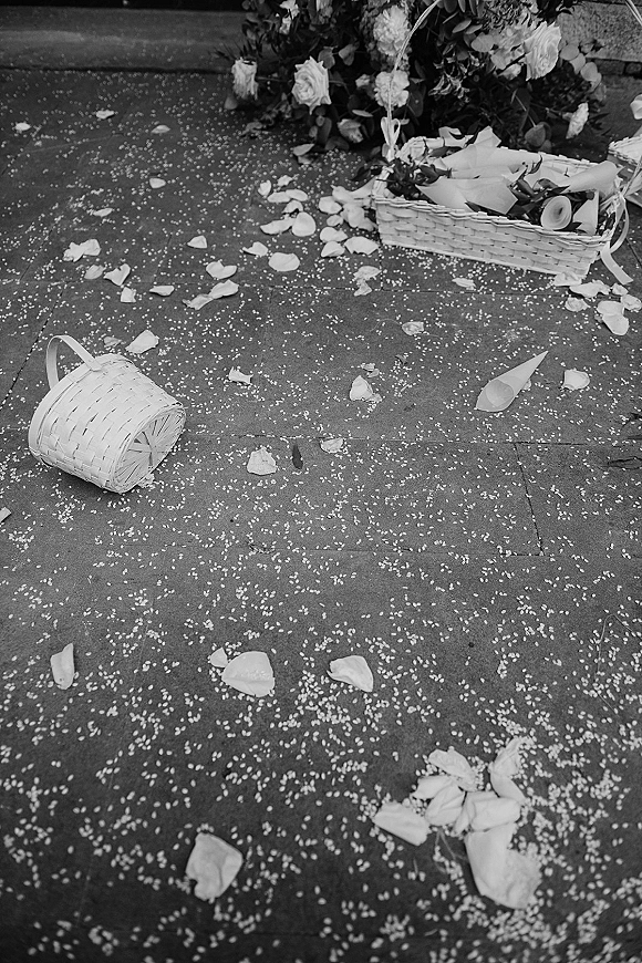 Wedding aisle confetti and rose petal aisle scattered on stone pavement beside a flower girl basket, paper cones, and steps