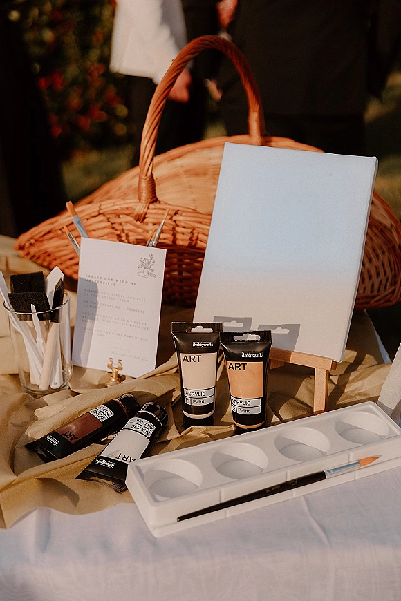 Wedding guestbook table set as a wedding guestbook alternative with blank canvas, acrylic paints and brushes on kraft paper in a garden setting