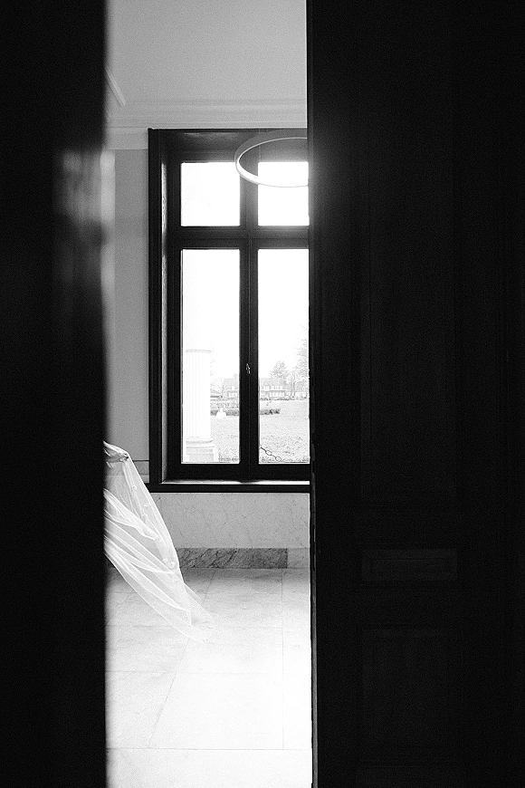 Bridal veil with cathedral veil train in soft window light, sheer tulle draped across a tiled floor through an interior doorway