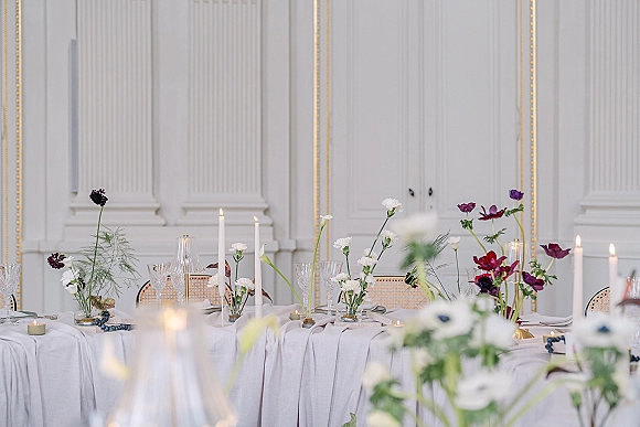 Reception tablescape with white linen tablescape, taper candle centerpiece, crystal glassware and grapes before white paneled doors with gold trim