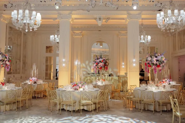 Reception tablescape with wedding reception table decor, round tables in white linens, gold chiavari chairs, tall florals and candlelight in a grand ballroom