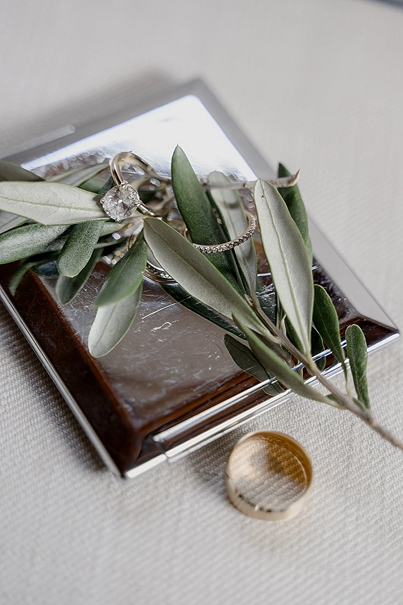 Wedding rings, engagement ring close up with diamond solitaire and gold band on mirrored ring box over linen fabric surface