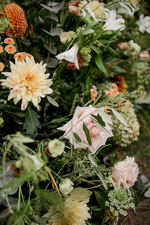 Wedding florals with dahlia wedding flowers in blush and peach hues, mixing roses, lisianthus, eucalyptus, and bell blooms against blurred greenery