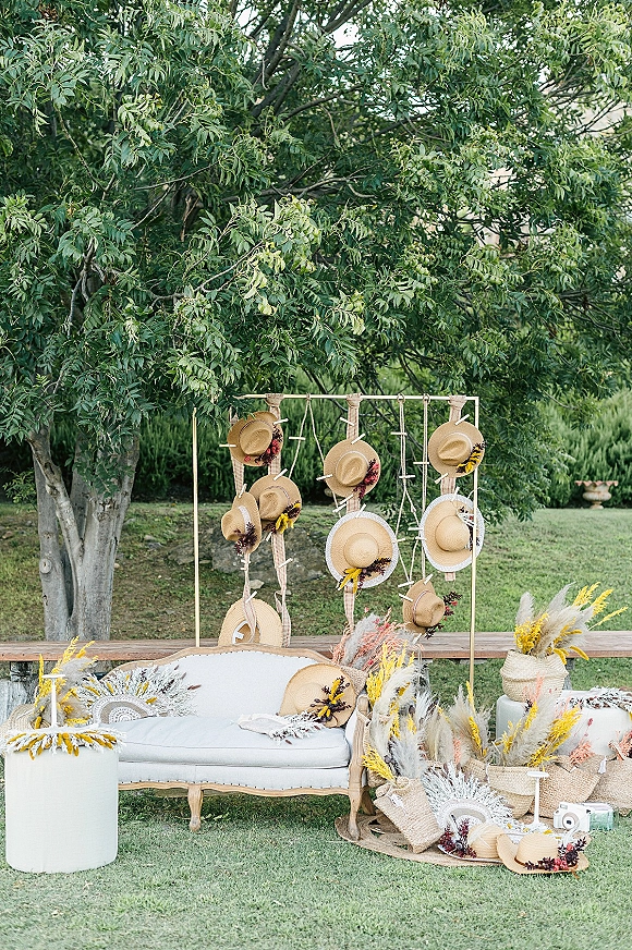 Wedding photo booth with outdoor wedding photo booth gold frame backdrop, hanging straw hats, white vintage sofa, pampas grass on garden lawn