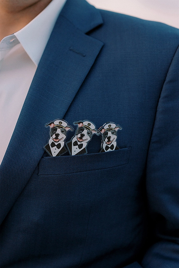 Groom pocket square with novelty pocket square dog and bow tie illustrations tucked into a navy suit jacket chest pocket close-up