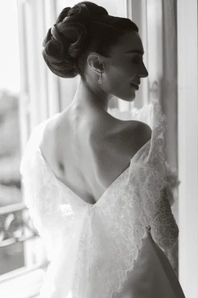 Bridal portrait in a black-and-white bride photo, the bride poses in a lace bridal gown, showcasing lace detail and texture.
