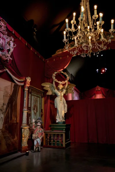 Wedding venue decor with a theatrical wedding backdrop, centered by a crystal chandelier on a moody stage with black ceiling and red walls.