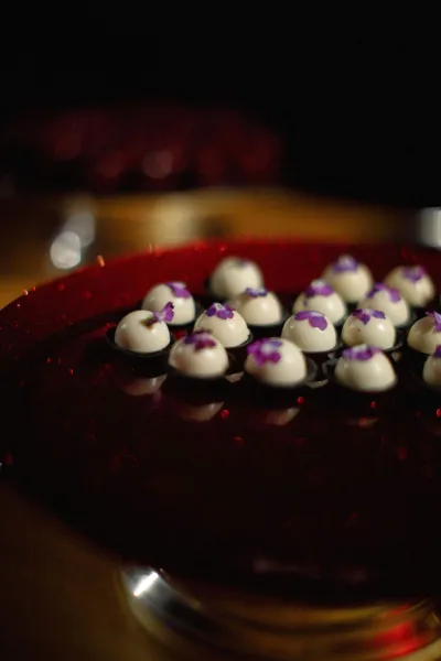 Mini wedding desserts arranged as a dessert bites display on a wedding dessert tray—a red serving platter—against a black backdrop and gold surface.