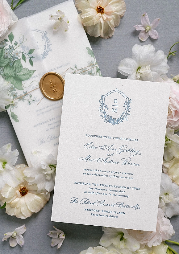 Wedding invitation suite with letterpress wedding invitations, floral liner, monogram crest, and gold wax seal on a gray fabric backdrop