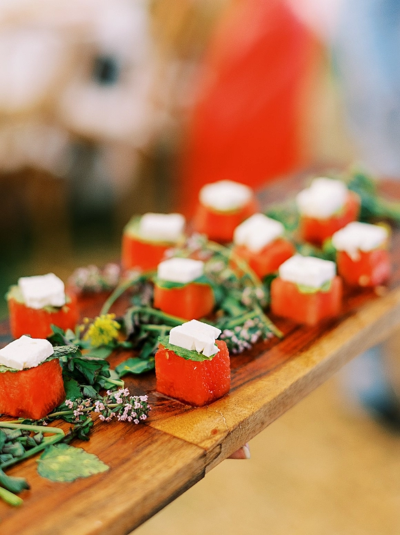 Wedding cocktail appetizers with passed appetizers wedding canapés on a wood serving board, herb garnish and edible flowers in warm reception light