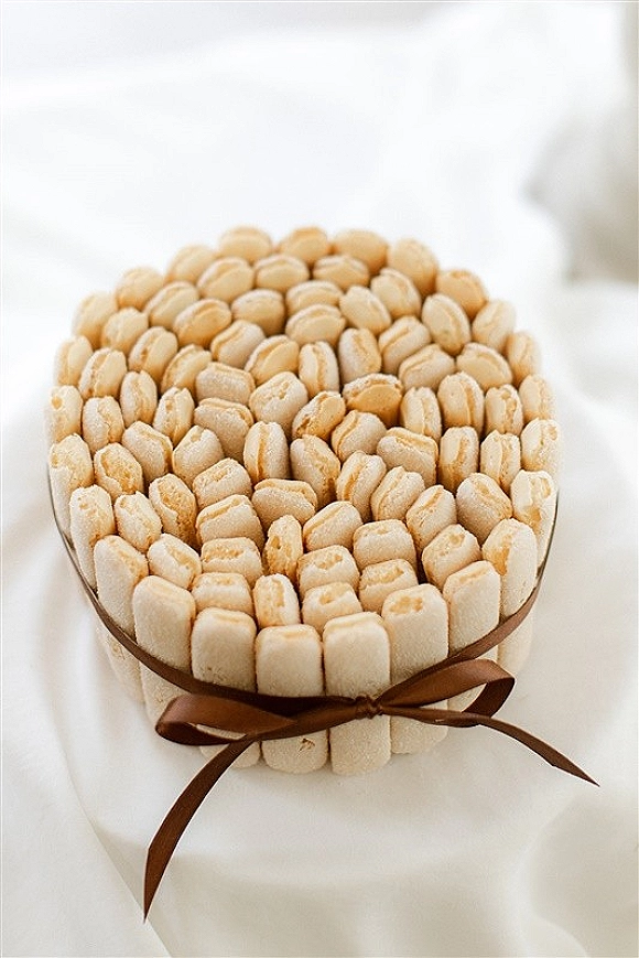 Wedding cookie favor with ribbon tied around stacked cookies on a white tablecloth, arranged as a simple edible wedding treat