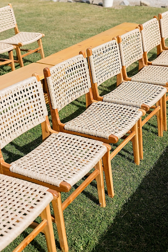 Ceremony seating with outdoor wedding seating in neat rows of woven chairs and wood benches arranged on a grass lawn, ready for guests