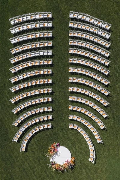 Ceremony seating arranged in curved ceremony rows around a round platform, creating a modern layout on a grass lawn for an outdoor ceremony.
