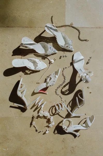 Bridal shoes in a wedding shoe flat lay, white slingback heels with pearl ankle strap and rhinestones on a sunlit stone floor