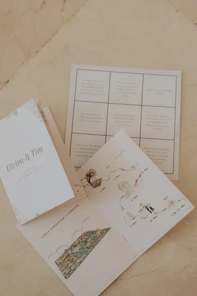 Wedding invitation suite flat lay with invitation, details and timeline cards, map insert, and envelope liner on marble surface