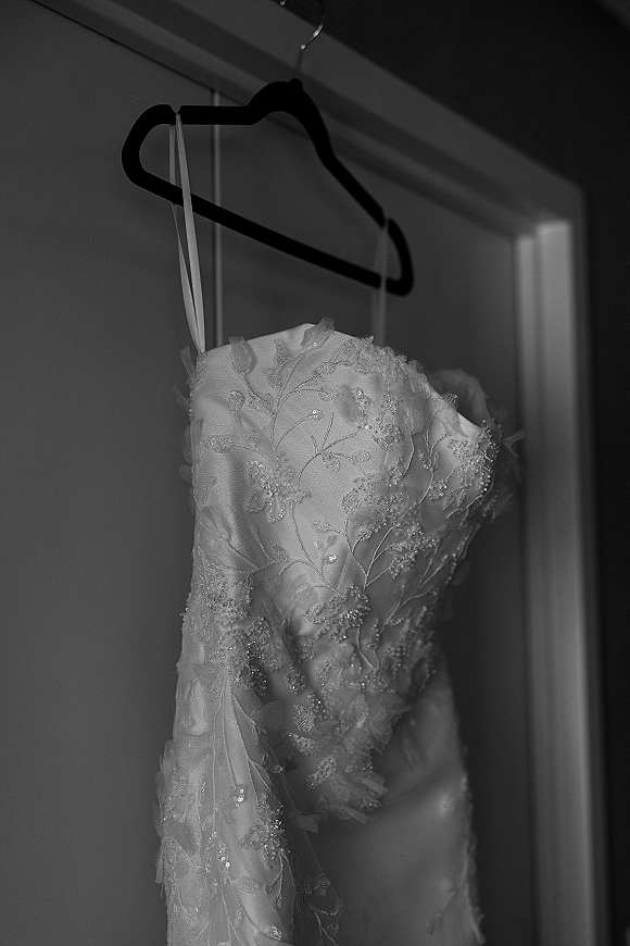 Wedding dress, lace wedding dress hanging on a hanger with spaghetti straps, lace appliqué and beading against a closet door indoors