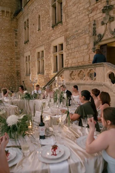 White calla lilies and taper candles decorate an outdoor reception dinner arranged along long tables