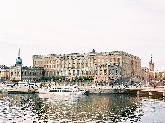 Waterfront palace view with historic palace waterfront across the river, a docked cruise boat and bridge beneath a pastel sky skyline