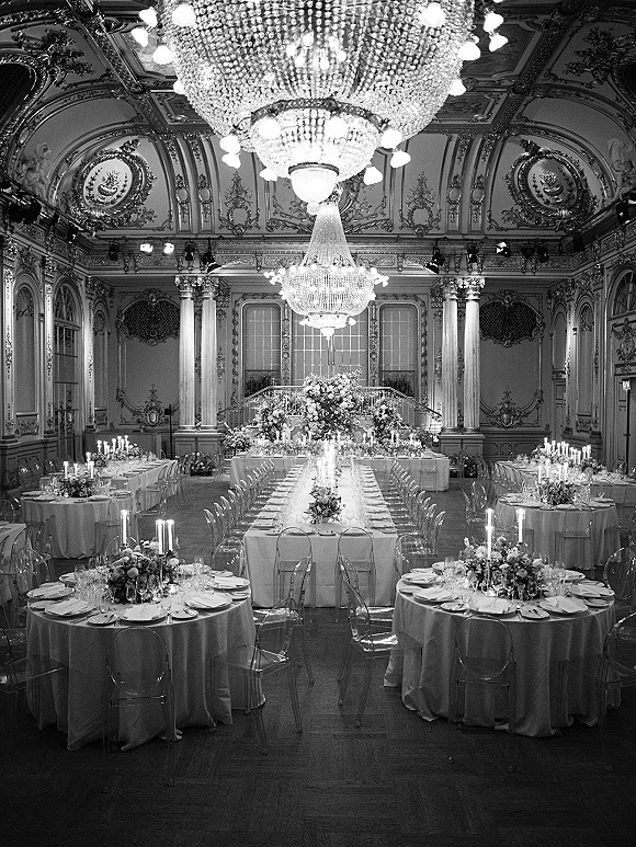 Reception ballroom decor with crystal chandelier wedding reception accents, candlelit banquet and round tables, florals, in an ornate gilded hall