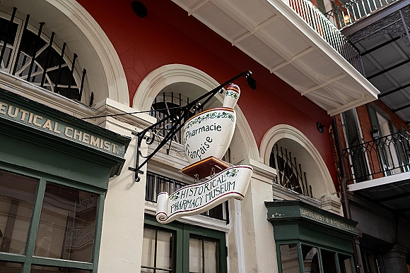 Wedding venue exterior with a hanging sign on a wrought iron bracket, arched windows and balconies on a red facade with white trim