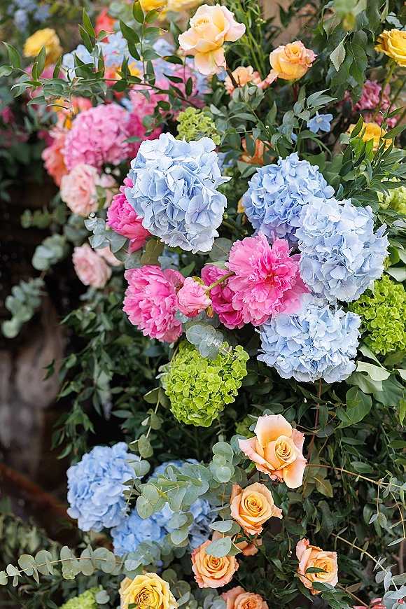 Wedding floral arrangement with hydrangea wedding flowers in pastel blues and pinks, framed by lush garden foliage in natural light