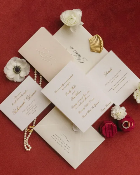 Invitation suite with a classic wedding invitation, styled with a velvet ring box on a rich red velvet fabric backdrop.