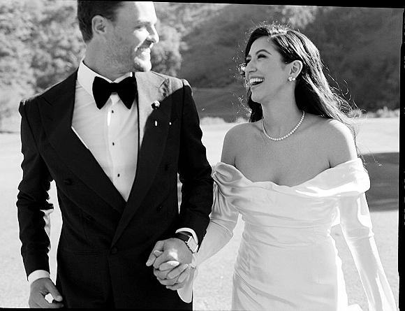 Couple portrait, black and white wedding portrait of bride and groom holding hands, smiling in an outdoor landscape with trees and hills