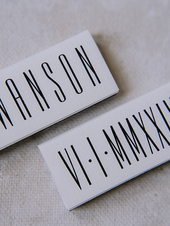 Wedding place cards with modern place cards styling, white cardstock and bold black typography arranged on neutral linen fabric background