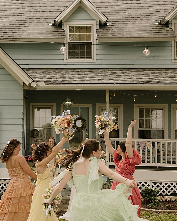 Bridesmaid portraits of a group holding bouquets in colorful dresses on a house porch, twirling under string lights and a disco ball﻿